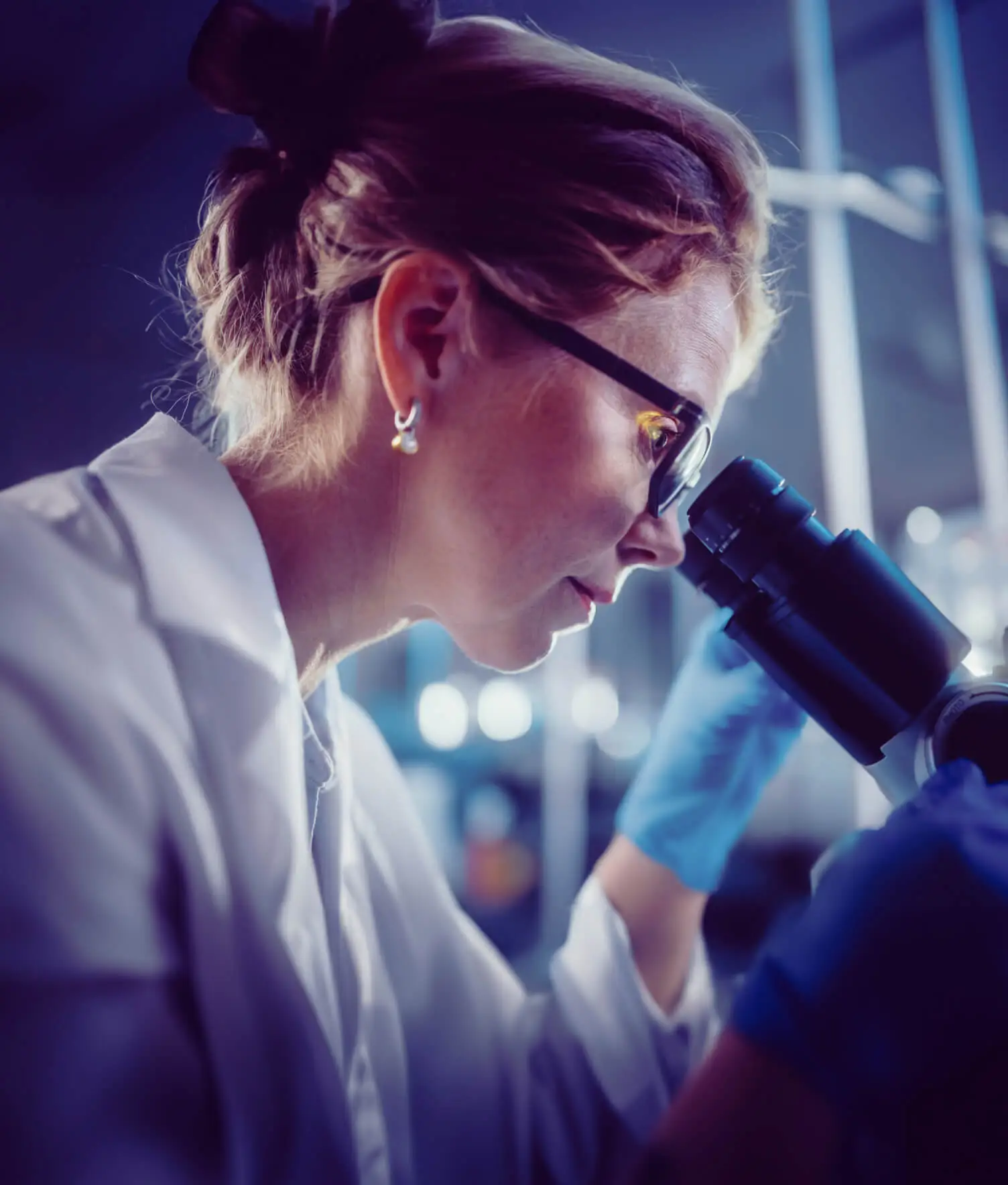 A scientist looks through a microscope.