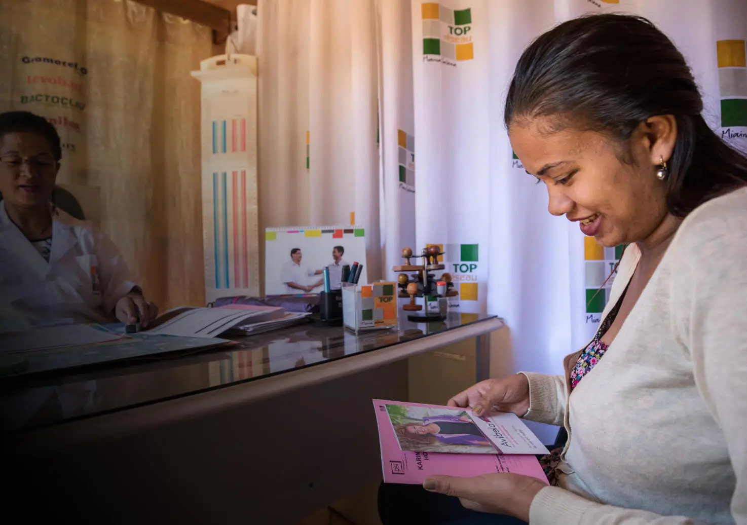 A woman smiles and looks at a photograph.